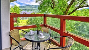 Een balkon met rieten stoelen, een glazen tafel en een plant in pot.