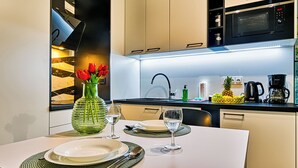 Une cuisine moderne avec une table à manger pour deux personnes, un vase rempli de fleurs rouges, un four à micro-ondes et une machine à café.