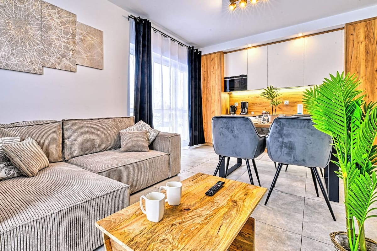 Ein modernes Wohnzimmer mit einer Couch, einem Couchtisch und einem Essbereich mit Stühlen.