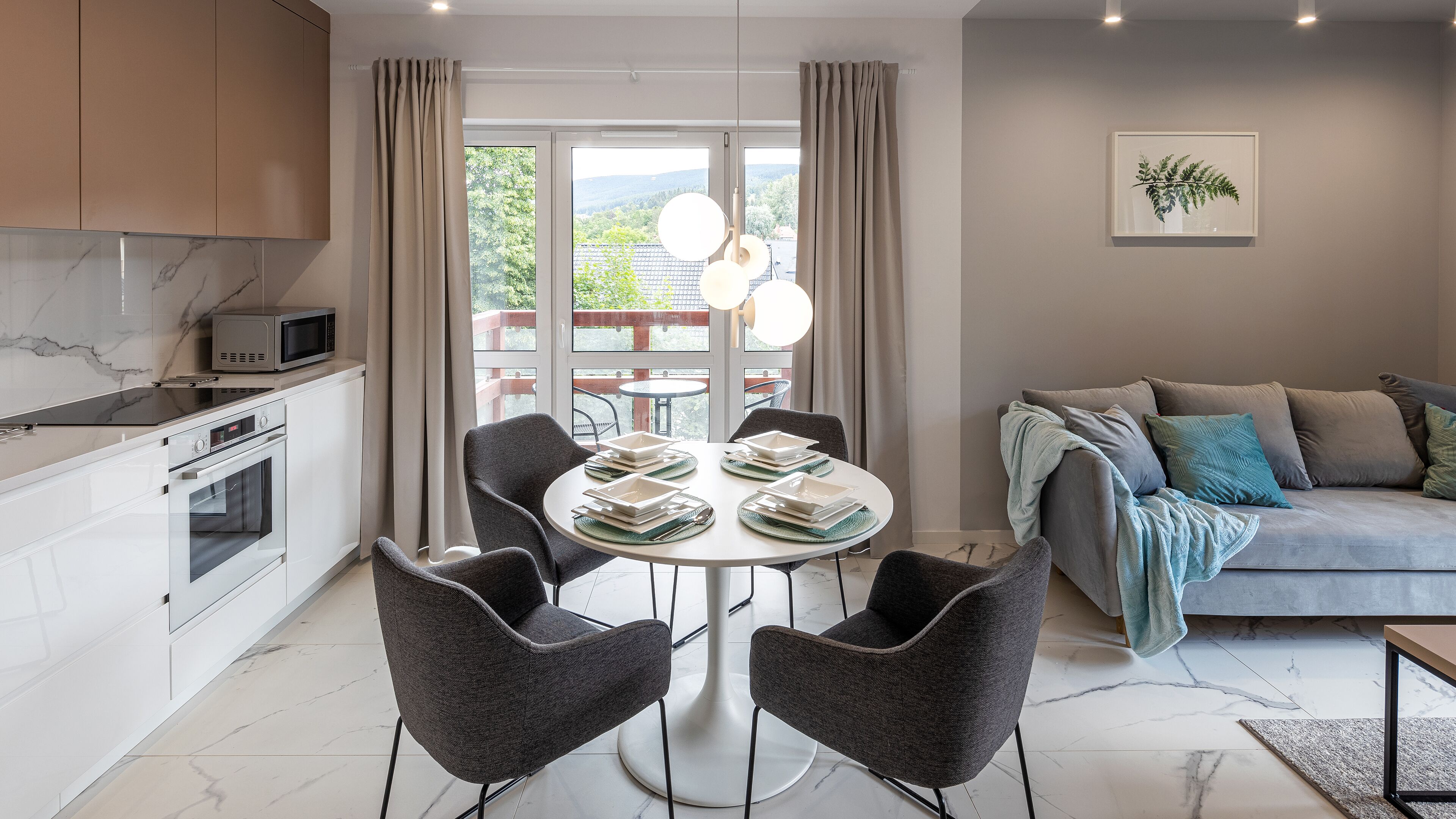 A modern kitchen with a microwave, oven, and dining area with a round table and four chairs.