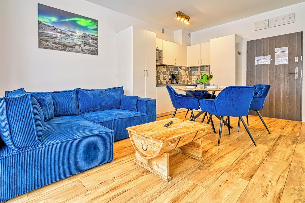 Ein modernes Wohnzimmer mit einem blauen Sofa, einem Holztisch und blauen Sesseln.