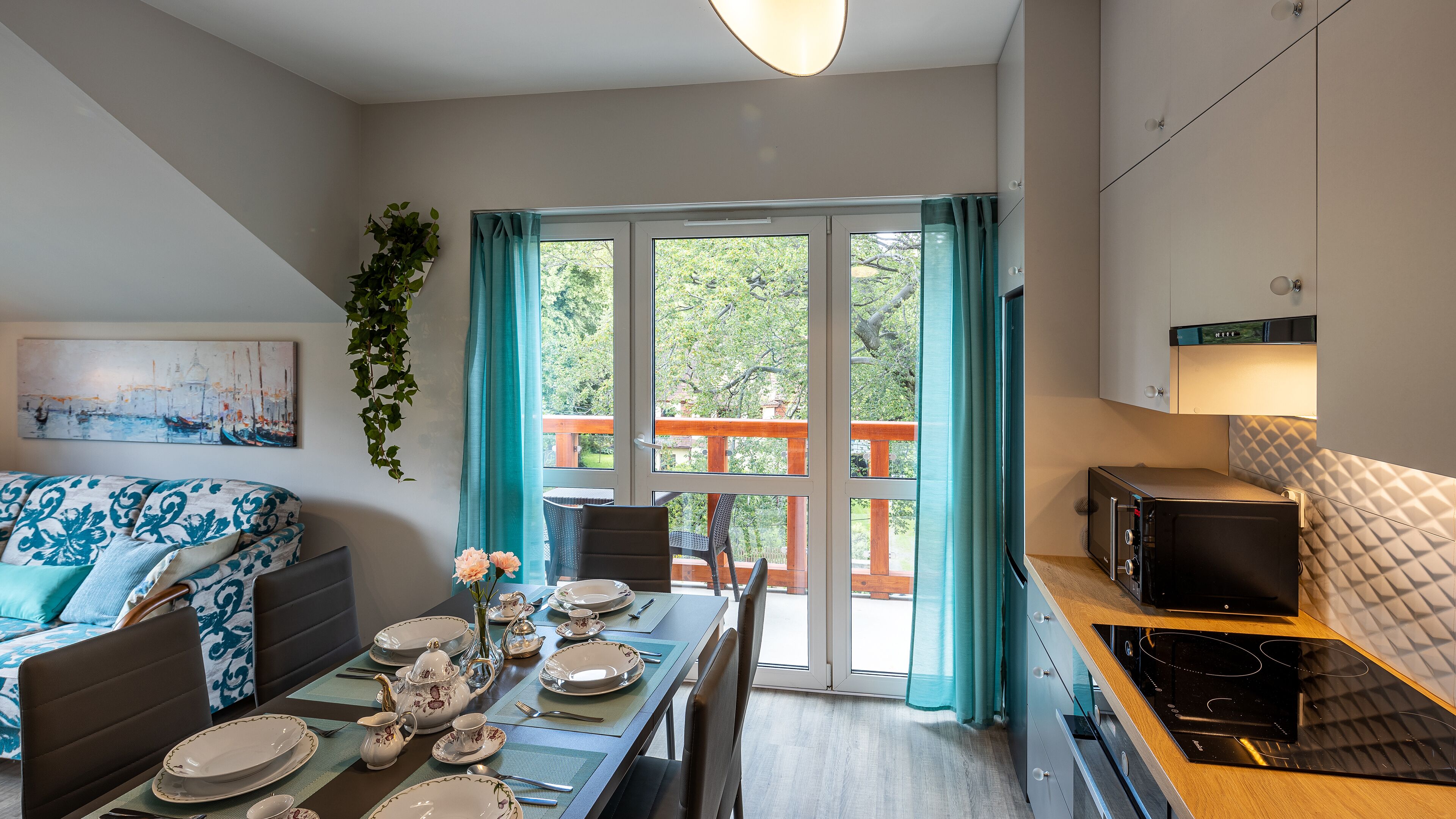A modern kitchen with a dining area, a sofa, and a view of a balcony.