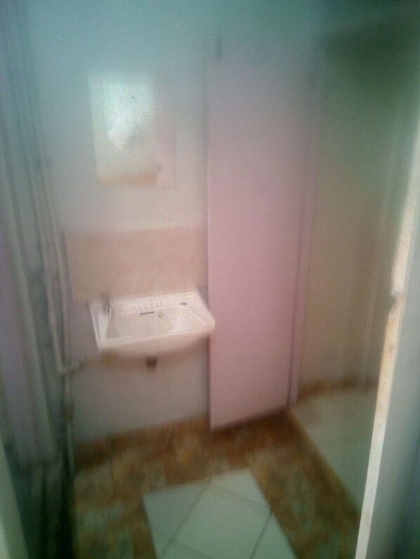 A small, dimly lit bathroom with a single sink and a toilet. - Nyeri Star Rest And Lodge (Nyeri)