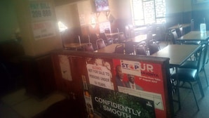 A restaurant with tables and chairs, a TV screen, and various signs including one for a political event. - Nyeri Star Rest And Lodge (Nyeri)