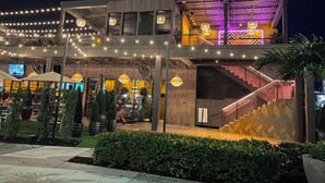 A multi-story building with outdoor seating, string lights, and a staircase.