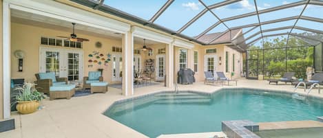 A covered outdoor pool area with lounge chairs and a patio table.