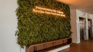 A wall with a green leafy design and a neon sign in Portuguese. - Hotel Go Inn  Goiana (Goiana)