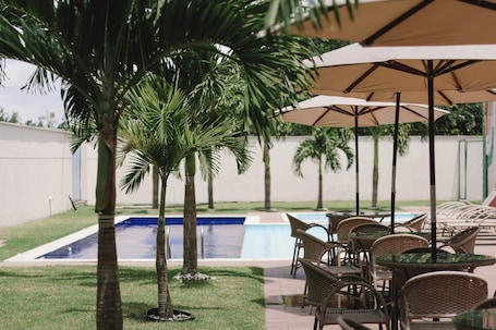 Una piscina al aire libre, sillones reclinables de piscina