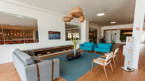 A modern lobby with a seating area, a bar visible through a large window, and a reception desk. - Hotel Go Inn  Goiana (Goiana)