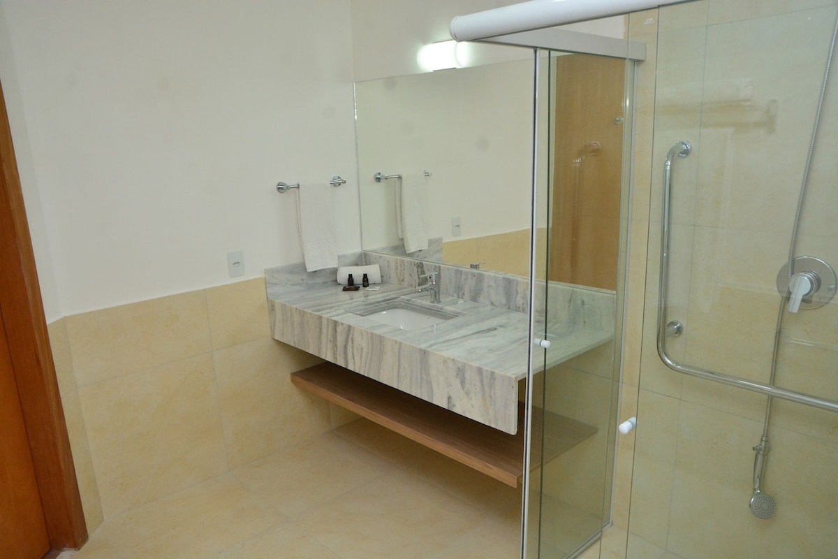 A modern bathroom with a glass-enclosed shower, a marble sink, and a large mirror.