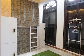 A room with a built-in wardrobe, a hanging clothes rack, and a window with a view.
