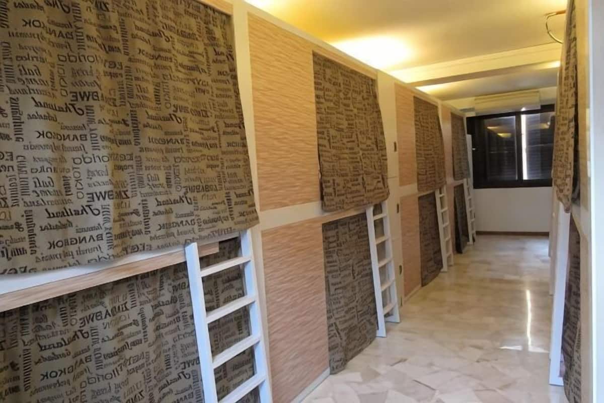 A hallway with patterned wallpaper, white shelves, and a tiled floor.