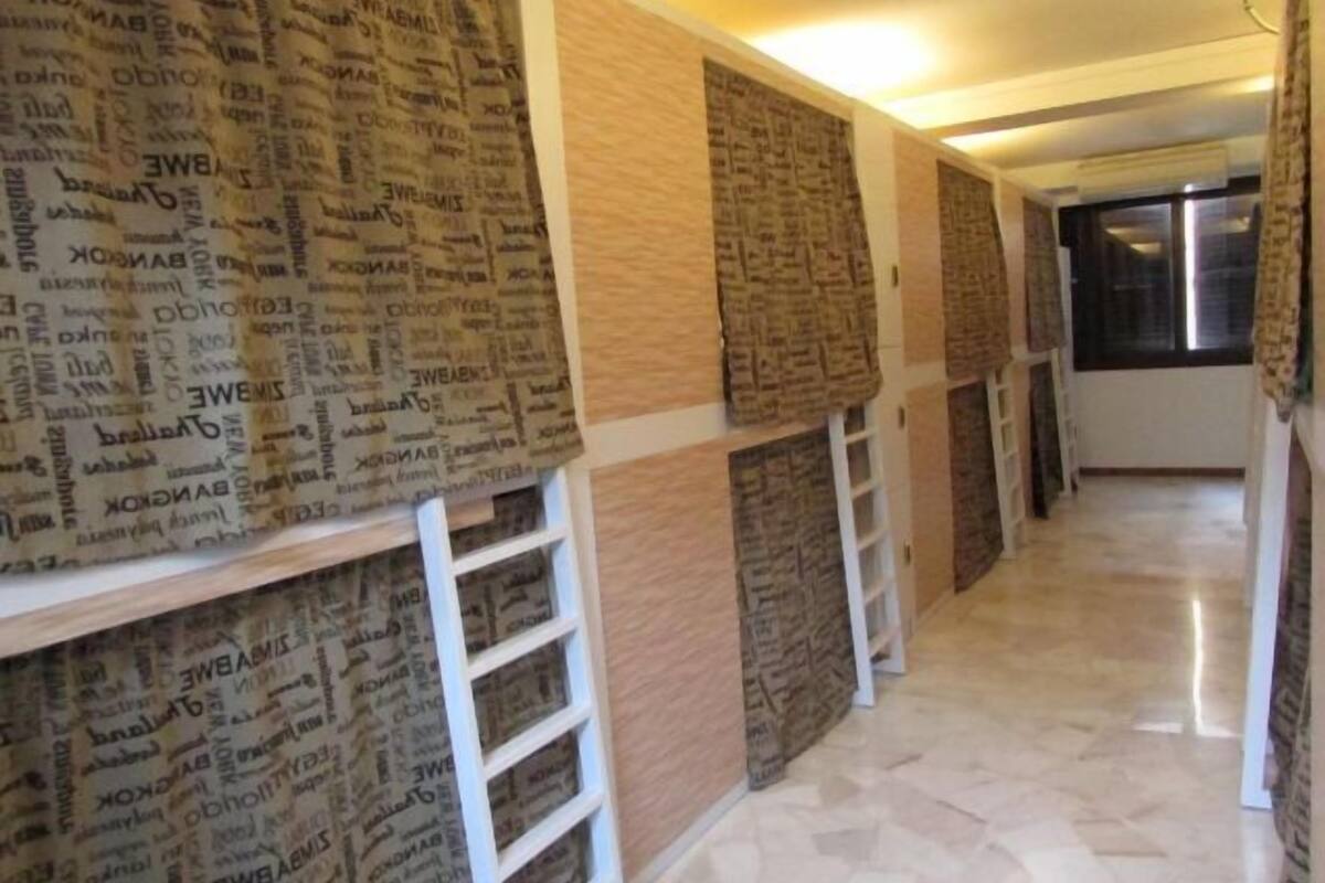 A hallway with patterned wallpaper, a white ladder, and a tiled floor.