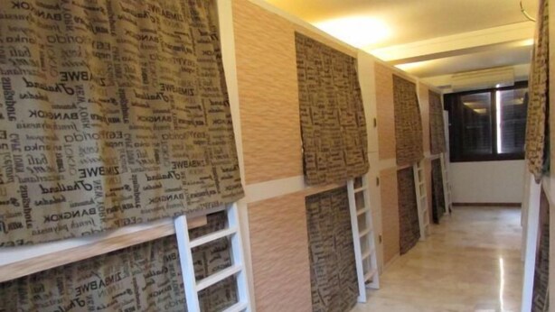 Un pasillo con papel tapiz estampado, una escalera de mano blanca y suelo de baldosas.