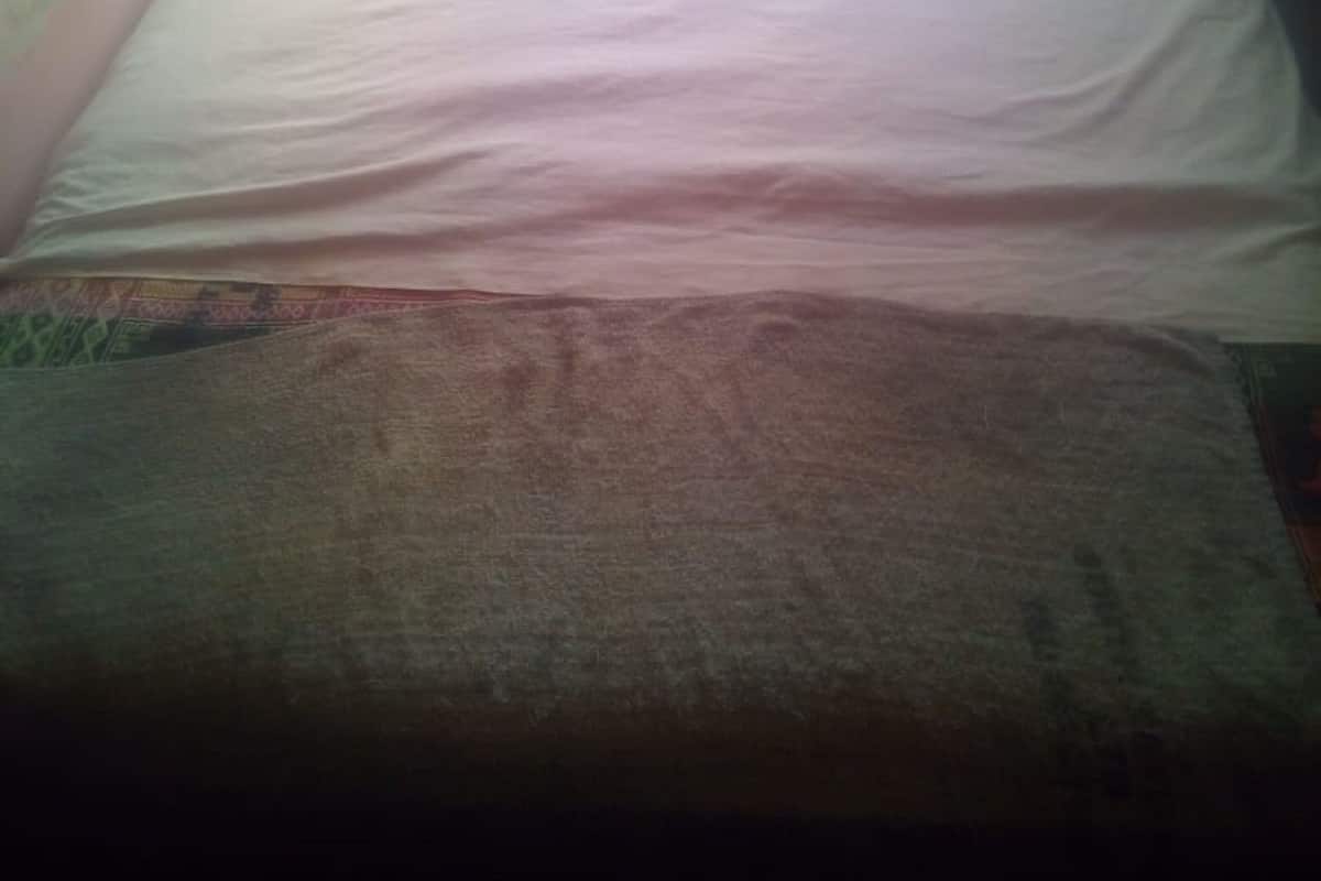 A small, dimly lit room with a single bed and a window.