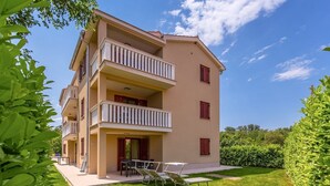 A multi-story building with balconies, a lawn, and outdoor furniture.