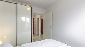 A bedroom with a bed, a wardrobe, and a door leading to a hallway.