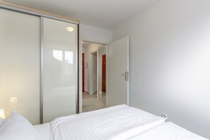 A bedroom with a bed, a wardrobe, and a door leading to a hallway.