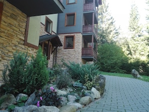 A multi-story building with stone and wood exterior, balconies, and a paved pathway leading to the entrance. - Fatrapark2 (Ruzomberok)