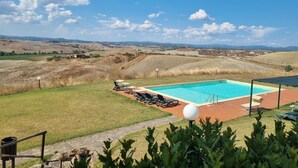 A swimming pool with lounge chairs, surrounded by a landscaped garden and a view of rolling hills. - STAFFOLINO Apartment 1                                        (siena)