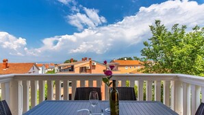 Una terraza con una mesa lista para dos, una botella de vino y una copa.
