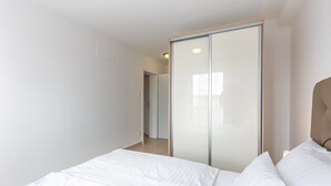 Un dormitorio con cama, armario y puerta que da a otra habitación.