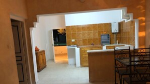 Cozinha com ilha central, armários de madeira e painel de azulejos.