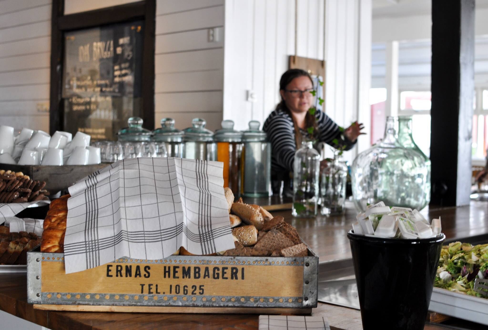 A bakery display with various baked goods and a sign reading "ERNAS HEMBAGERI TEL. 10625".