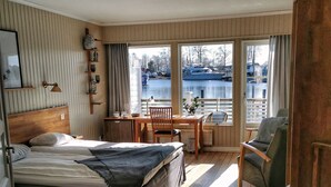 A hotel room with a bed, a desk, a chair, and a view of a body of water.