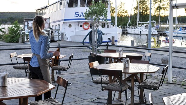 A waterfront restaurant with outdoor seating overlooking a marina.