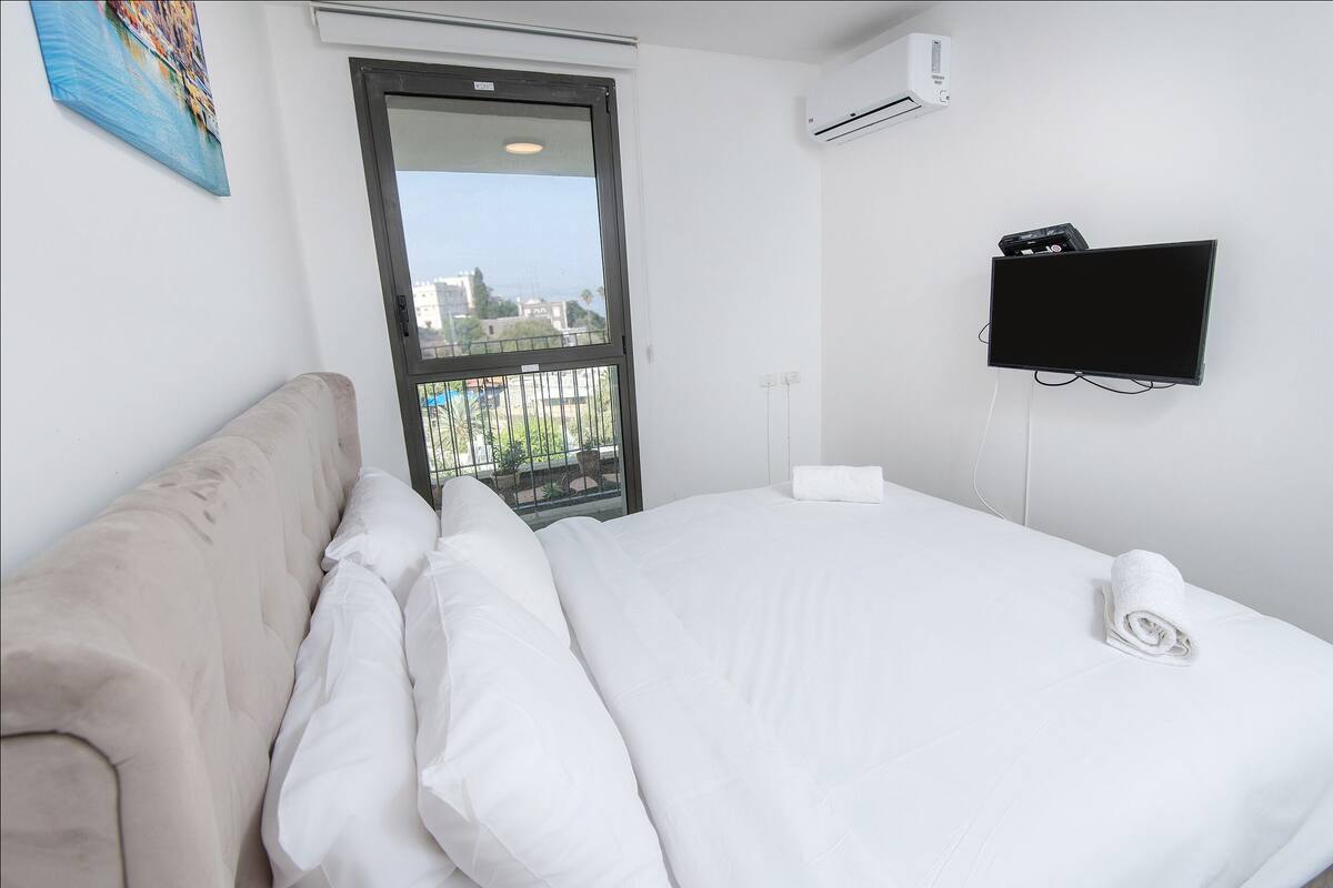 Habitación de hotel con cama, ventana con vistas, televisor montado en la pared y aire acondicionado.