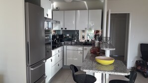 A modern kitchen with stainless steel appliances, white cabinetry, and a granite countertop. - T3, 60 m2, small building with swimming pool, 1st floor, separate entrance (Collioure)