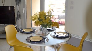A dining area with a round table, yellow chairs, and a vase with yellow flowers. - T3, 60 m2, small building with swimming pool, 1st floor, separate entrance (Collioure)