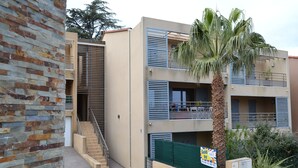 A two-story building with a brick facade, a palm tree, and a 'Sold by' sign. - T3, 60 m2, small building with swimming pool, 1st floor, separate entrance (Collioure)