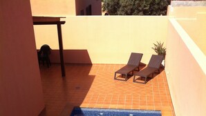 A rectangular swimming pool with a tiled deck, two lounge chairs, and a small table. - RELAX AND TRAQUILADAD pair all kinds of families with or without children  (corralejo)