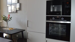 Una cocina con horno y microondas integrados, una mesa de comedor con un florero y un espejo montado en la pared.
