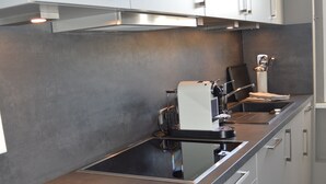 Una cocina moderna con armarios blancos, encimera de acero inoxidable y horno empotrado.