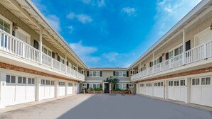 A multi-story building with a central courtyard, white balconies, and a brick facade. - Oceanfront on Dry Sandy Carbon Beach - Sandpiper (Malibu)