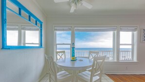 A room with a white table and chairs, a blue-framed window, and a view of the ocean. - Oceanfront on Dry Sandy Carbon Beach - Sandpiper (Malibu)