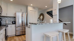 Una cocina moderna con electrodomésticos de acero inoxidable, encimera de mármol y armarios blancos.