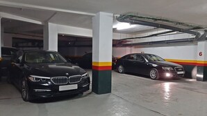 Ett parkeringsgarage med två parkerade bilar, betongpelare och ett tak med synliga rör.