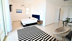 Un dormitorio moderno con una cama grande, una mesita de noche, una silla, un tapete a rayas negras y blancas y una lámpara colgante.