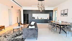 Una sala moderna con un sofá gris, una mesa de centro y un comedor con una mesa y sillas de madera.