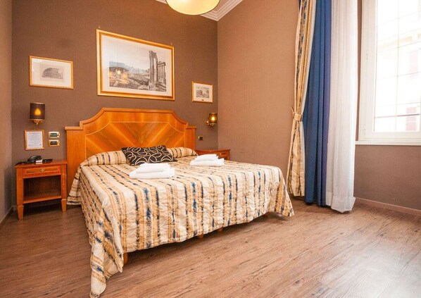 Une chambre d’hôtel avec un grand lit, une tête de lit en bois et une vue sur la ville par la fenêtre.