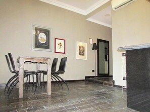 A dining area with a wooden table and chairs, framed artwork on the wall, and a dark tiled floor. - Vatican Top Accommodation (Rome)