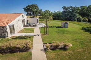 A stone house with a tiled roof, a paved pathway, and a grassy yard with a small tree and a stone structure. - Demeure du Pont Rolland, heated inside pool, sauna and great location (Avrillé)