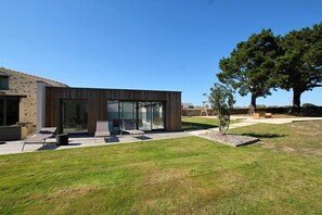 A modern building with a glass facade, outdoor seating area, and a well-maintained lawn.