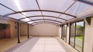 Un espacio al aire libre techado, con piso plano, amplios ventanales y una estructura de techo curva.