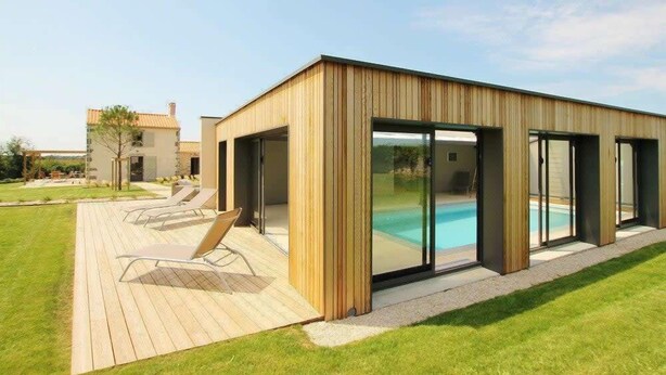 Un edificio moderno con área de piscina, que incluye una terraza y sillones de descanso.