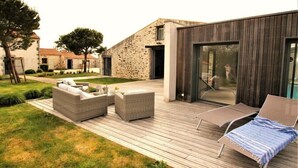 Un patio moderno al aire libre con mobiliario de mimbre y una puerta de vidrio que da a una zona de piscina.